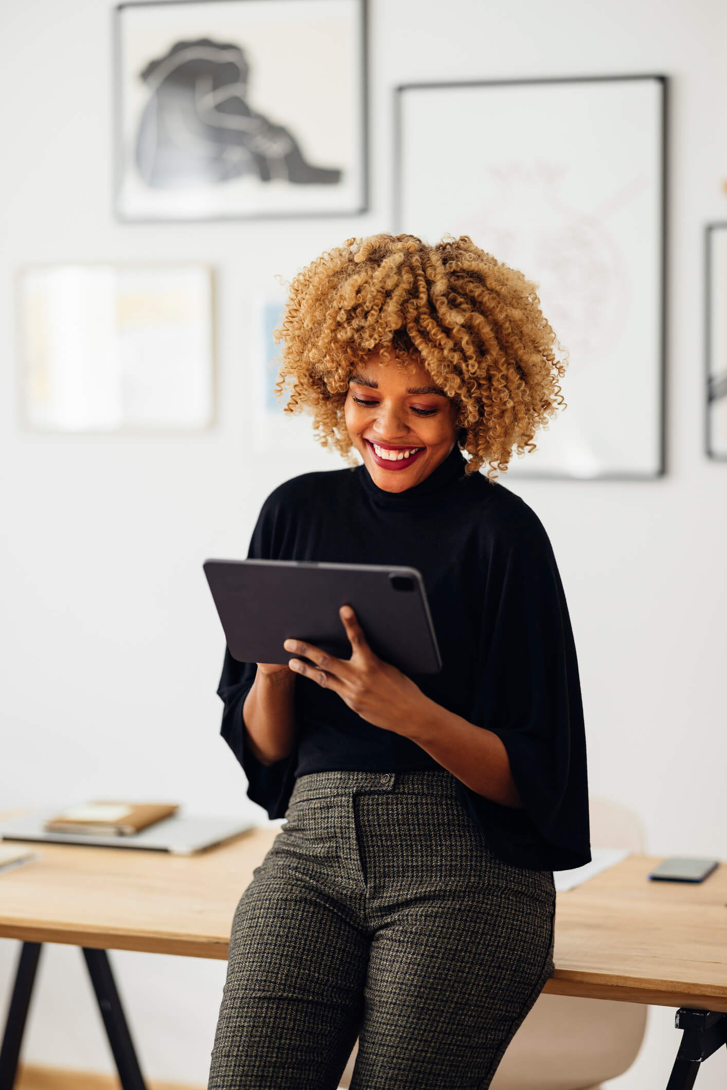 black woman smiles at tablet in her office